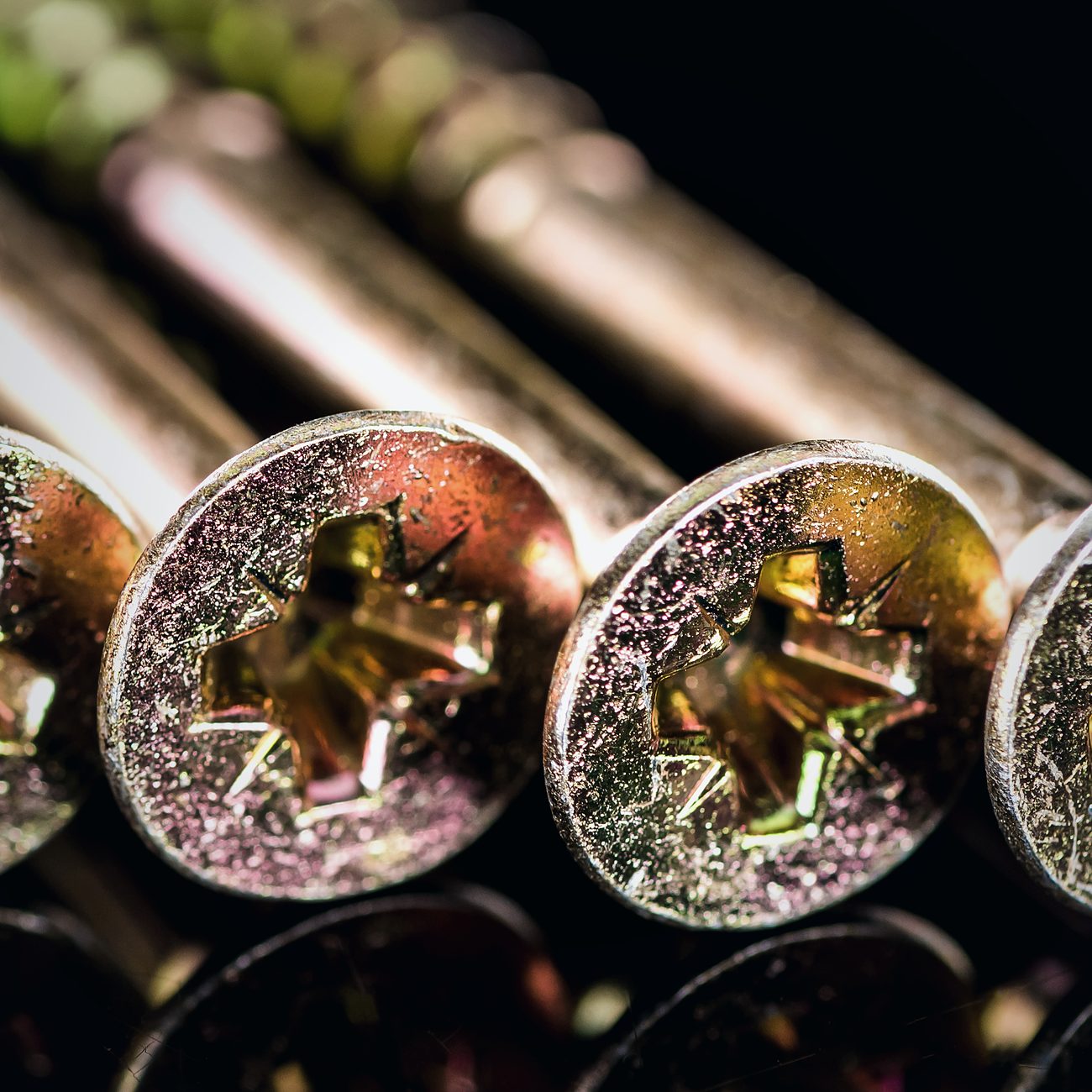 Close-up of yellow zinc-plated screw heads on a black background